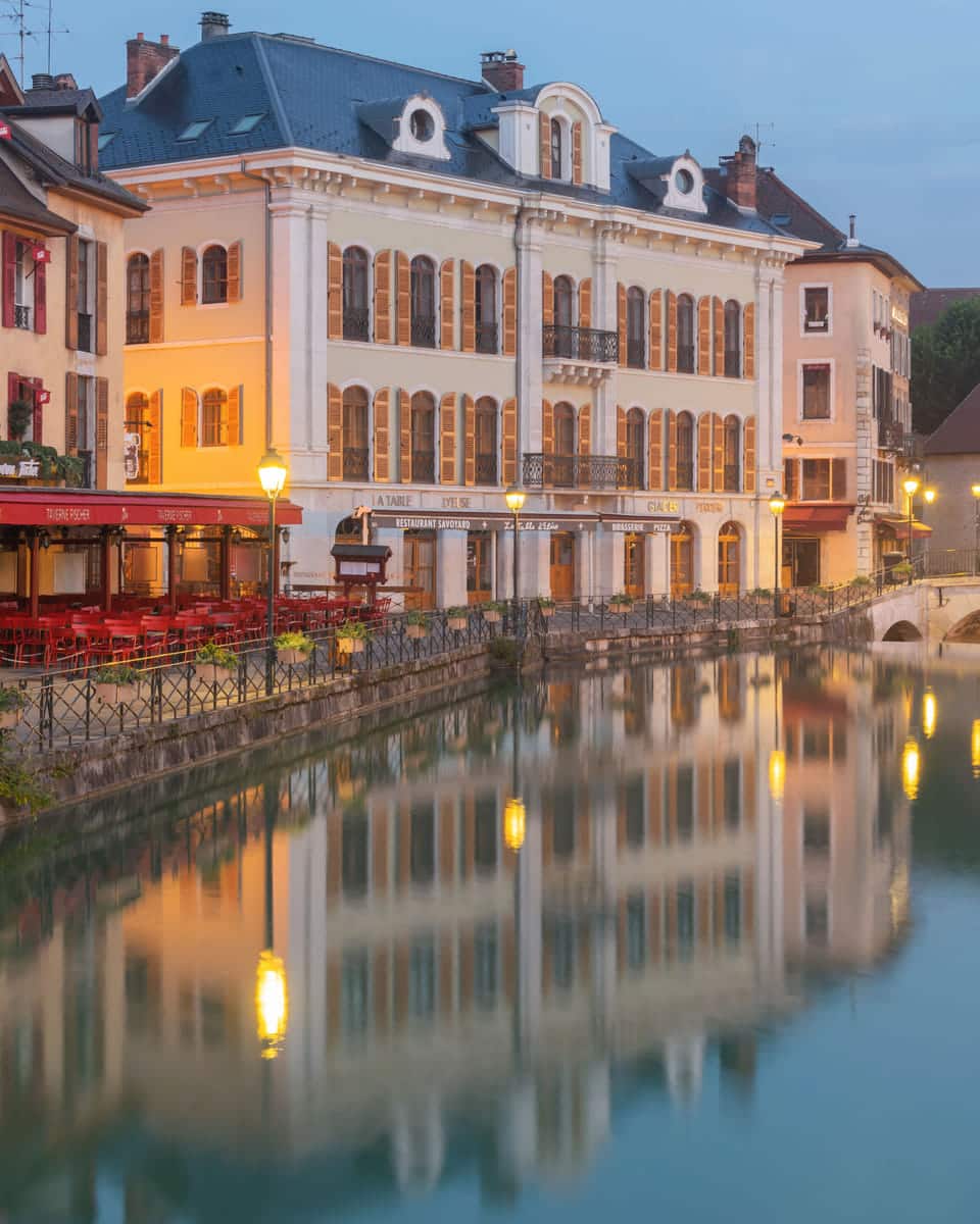 The pastel façades and red shutters of the quai Perrière at dawn, reflected in the canal.